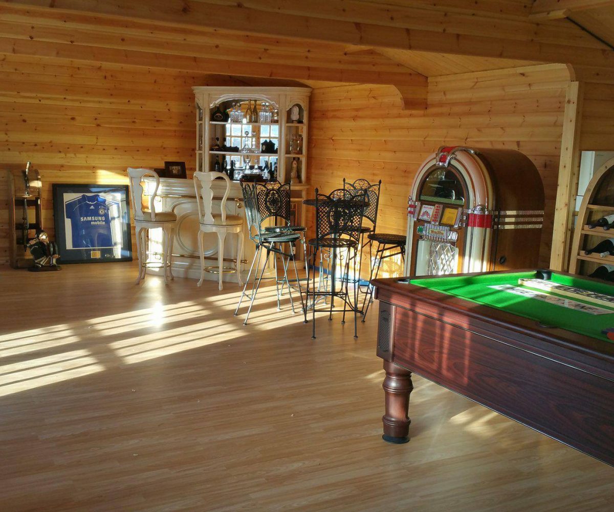 Log cabin interior, furnished with snooker table, wine rack, jukebox and table and chairs.