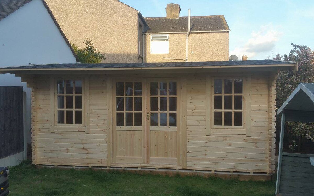 Apex roof log cabin with double doors, two front windows and apex style roof, situated in customer garden.