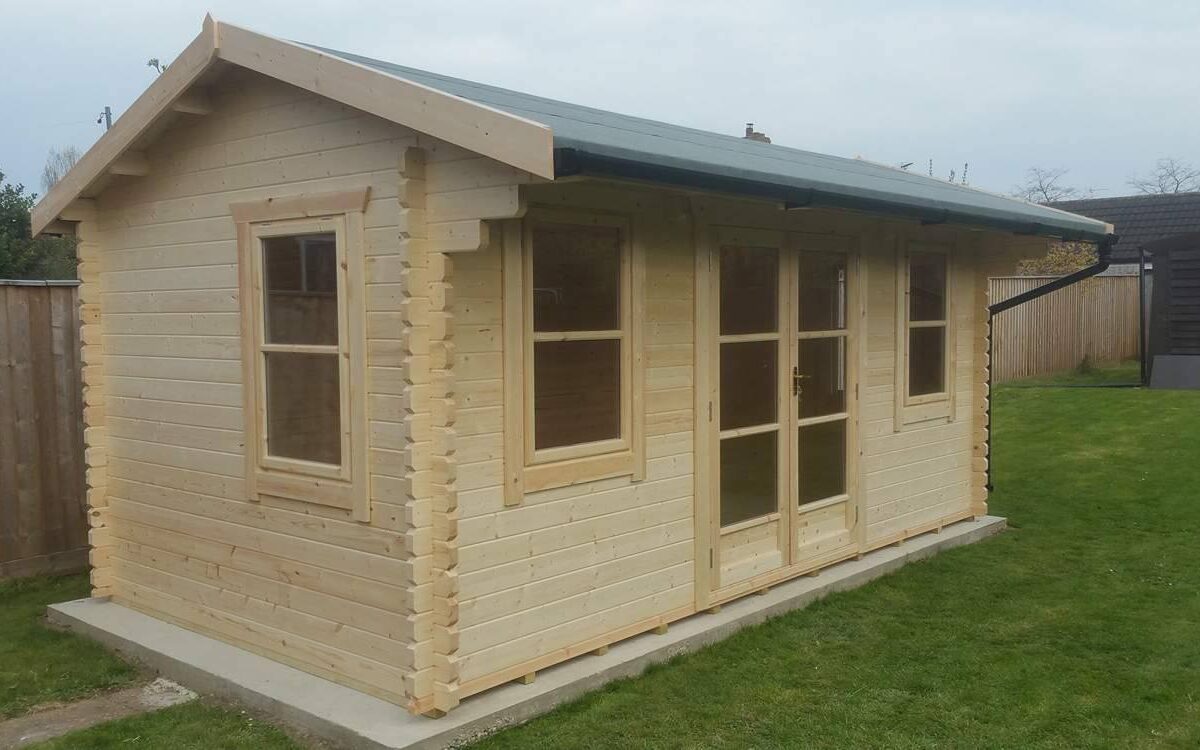 Log cabin with double doors, windows at the front and side, apex roof and guttering, situated in a garden.