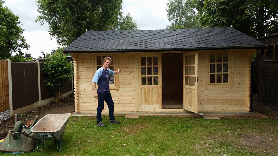 Newly constructed log cabin with half glazed double doors, two front windows and apex roof.