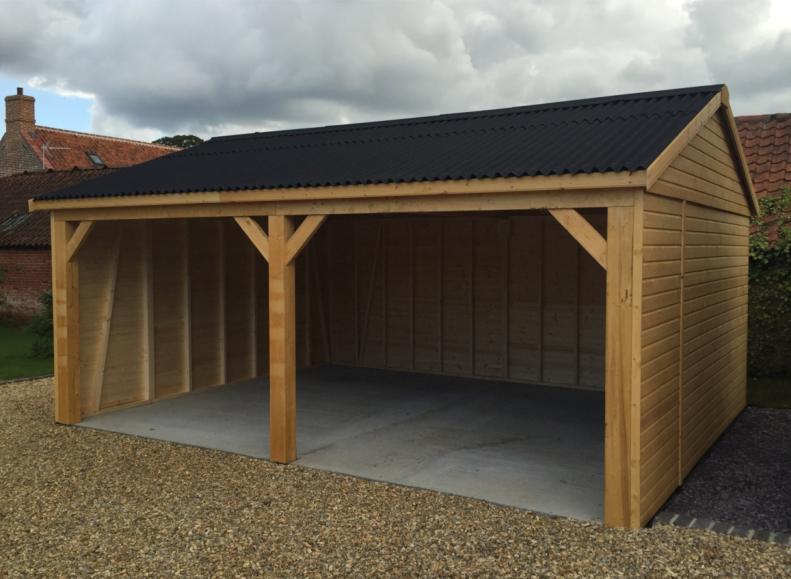 Wooden carriage house with apex roof, situated in a back garden.