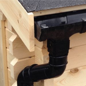 Black guttering and pipe on roof of log cabin.